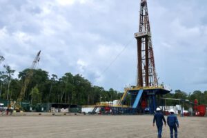 Fotografía de archivo de operarios frente a torre de perforación de pozos petroleros