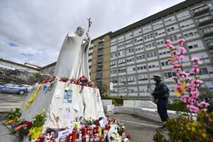 Un fiel reza frente a la estatua de Juan Pablo II en el Hospital Gemelli donde el Papa Francisco está hospitalizado