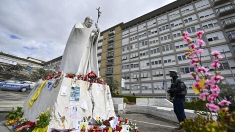 Un fiel reza frente a la estatua de Juan Pablo II en el Hospital Gemelli donde el Papa Francisco está hospitalizado