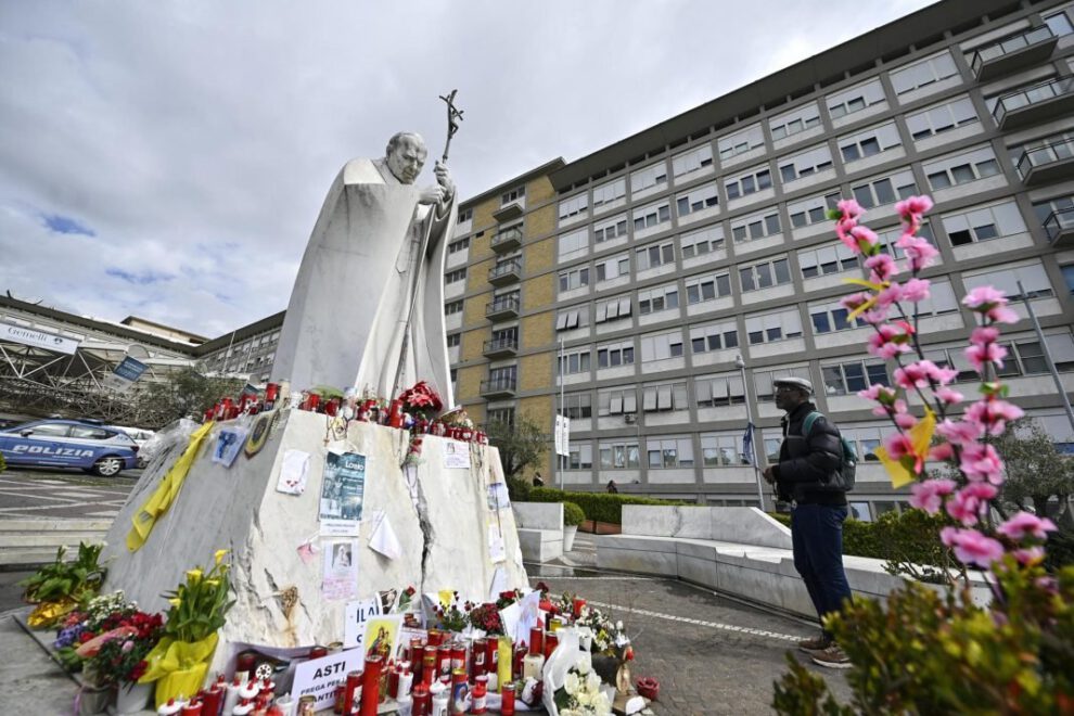 Un fiel reza frente a la estatua de Juan Pablo II en el Hospital Gemelli donde el Papa Francisco está hospitalizado