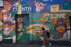 Una persona camina frente a un mural alusivo a la niñez