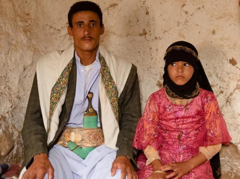 Una niña posando al lado de un hombre mayor
