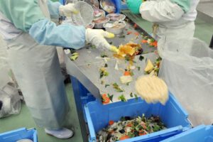 Varios empleados de la planta de reciclaje de alimentos Agri Gaia System Co. Ltd. separan la comida pasada de fecha