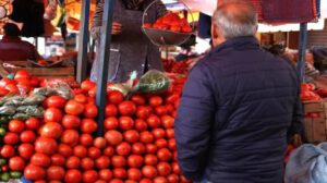 señor en una mercado comprando tomate
