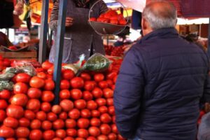 señor en una mercado comprando tomate