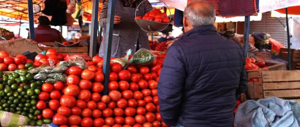 señor en una mercado comprando tomate