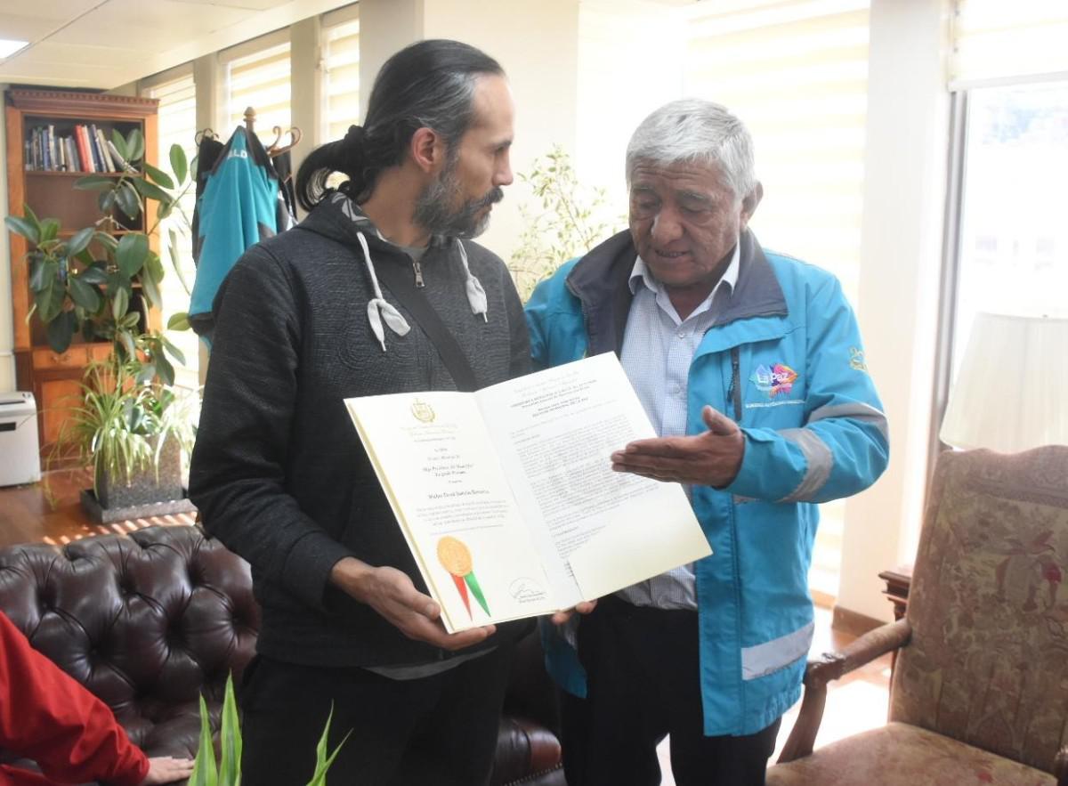El momento en que Yungaro Santalla recibe de manos del alcalde de La Paz, Iván Arias, el diploma y la medalla que acreditan a su padre, David Santalla, como 