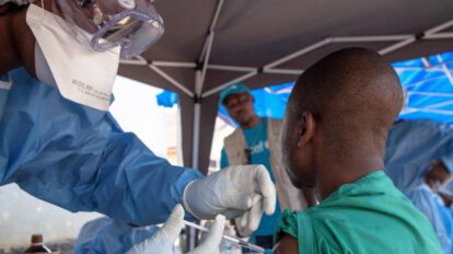Trabajador de la salud le inyecta la vacuna contra el ébola a un paciente