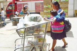 Una mujer con su niño recoge algunos productos del subsidio materno infantil