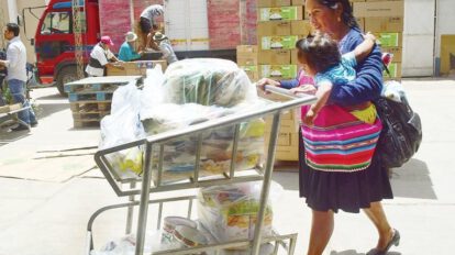 Una mujer con su niño recoge algunos productos del subsidio materno infantil