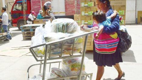 Una mujer con su niño recoge algunos productos del subsidio materno infantil