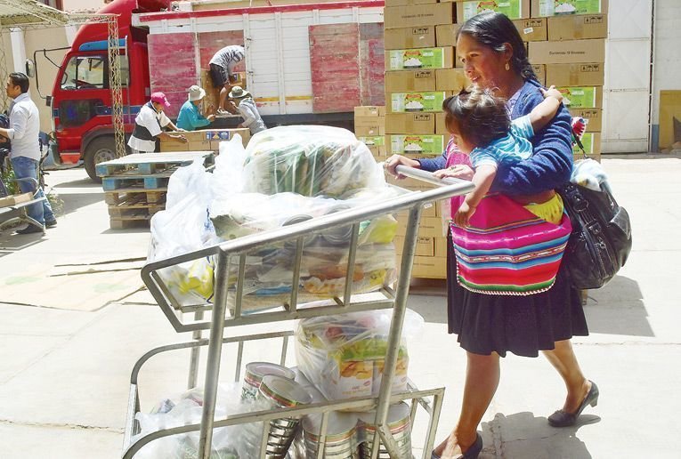 Una mujer con su niño recoge algunos productos del subsidio materno infantil