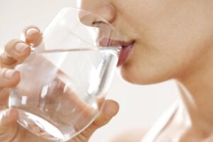 Una joven mujer bebiendo agua para mantenerse hidratada