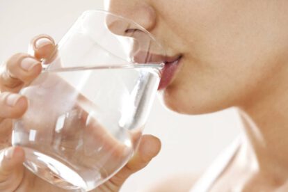Una joven mujer bebiendo agua para mantenerse hidratada