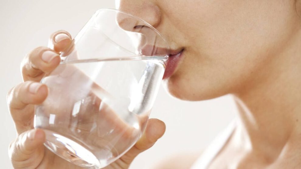 Una joven mujer bebiendo agua para mantenerse hidratada