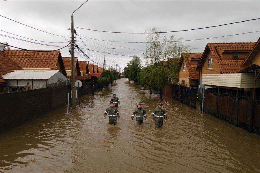 Tragedia climática en Chile: Rescatistas caminan por una calle inundada tras el desborde del río Claro