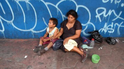 Niño salvadoreño de escasos recursos junto a su madre sobre los Objetivos de Desarrollo Sostenible