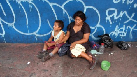 Niño salvadoreño de escasos recursos junto a su madre sobre los Objetivos de Desarrollo Sostenible