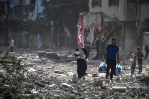 Una familia palestina entre los escombros de los edificios alcanzados en un bombardeo israelí sobre el barrio de Tel al-Hawa, en Gaza