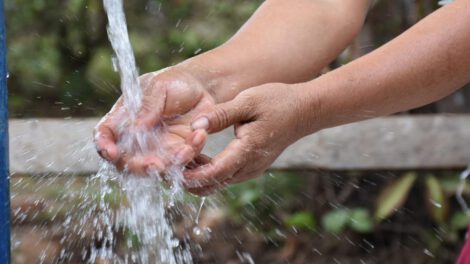 Una persona lavándose las manos en un grifo de agua