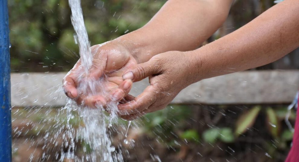Una persona lavándose las manos en un grifo de agua