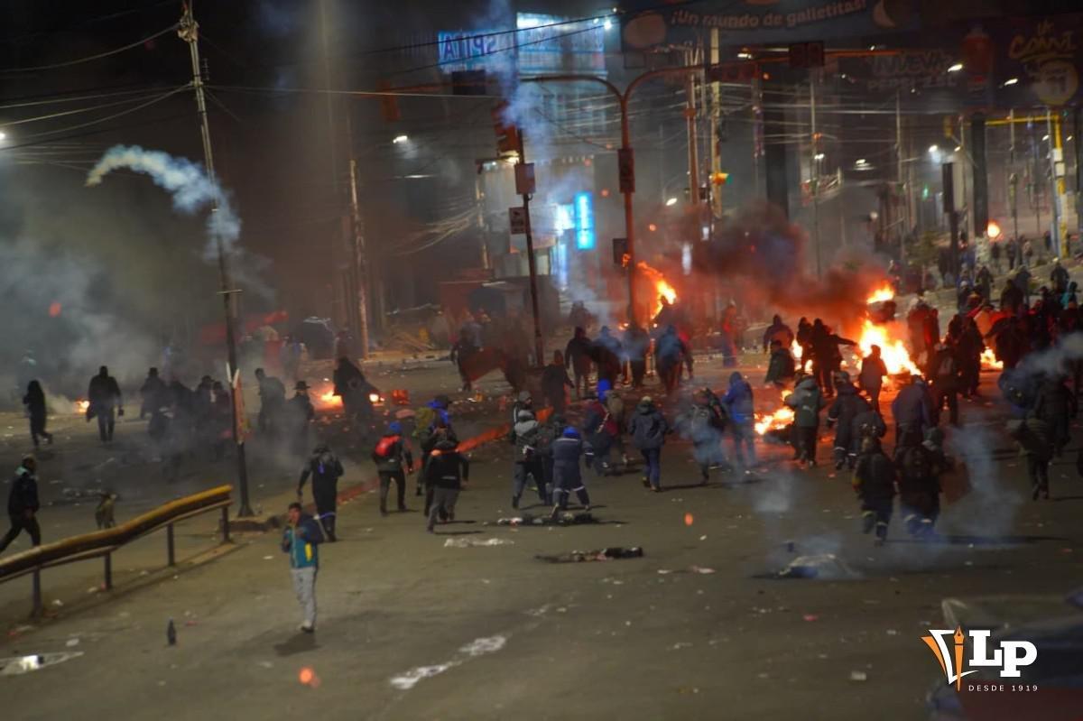 Escena de enfrentamientos nocturnos con presencia de fuego y gases lacrimógenos en las calles