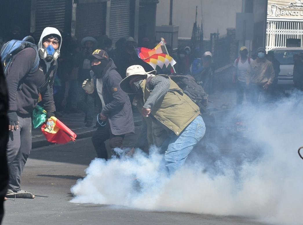 Manifestantes en medio de una nube de gas lacrimógeno durante los enfrentamientos
