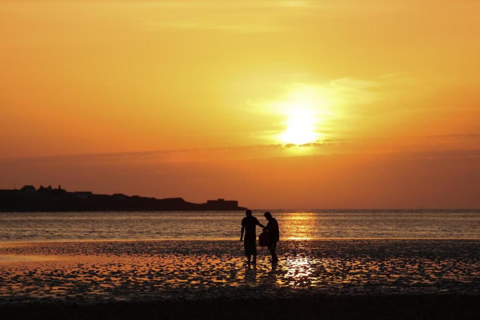 Personas pasean por una playa West Kirkby (Reino Unido), en una jornada calurosa