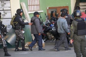 Un agente de la policía conduce a detenidos