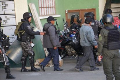 Un agente de la policía conduce a detenidos