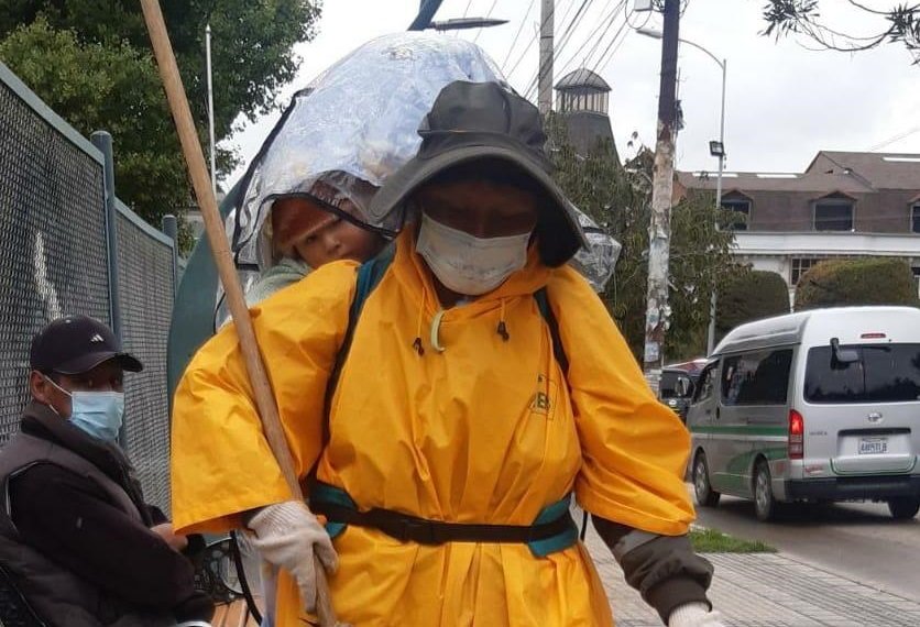 Nemecia limpia las calles junto a su pequeño hijo que lleva en la espalda