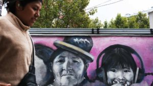 Una persona caminando frente a un mural con el dibujo de una niña en La Paz (Bolivia)