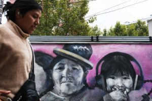 Una persona caminando frente a un mural con el dibujo de una niña en La Paz (Bolivia)