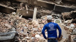 Una persona observa a una víctima entre los escombros de un edificio