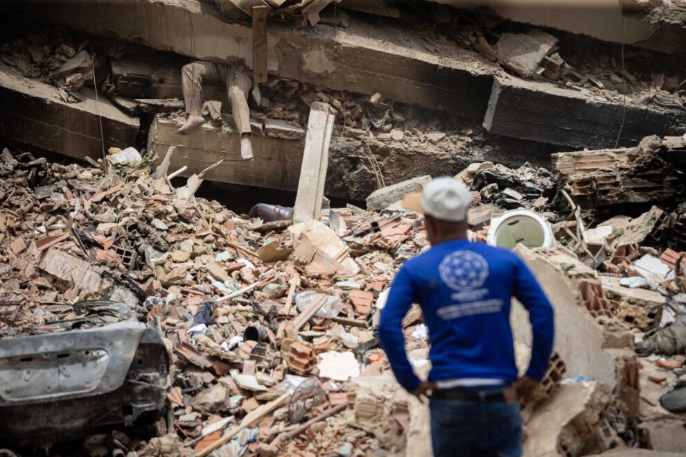 Una persona observa a una víctima entre los escombros de un edificio