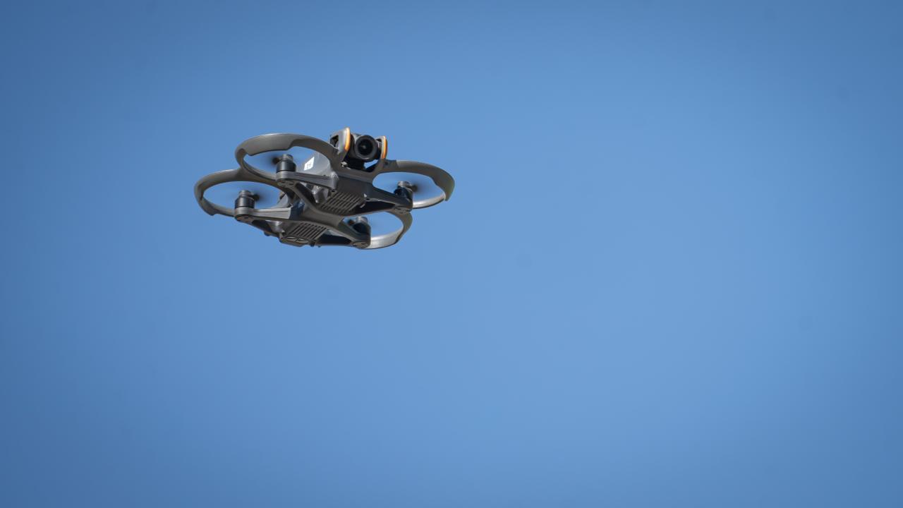 El dron cuadricóptero DJI Avata vuela en el cielo azul durante la presentación