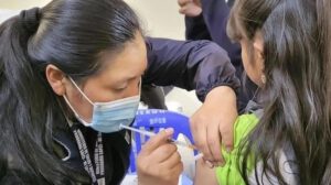 Una mujer vacunando a una niña