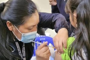 Una mujer vacunando a una niña