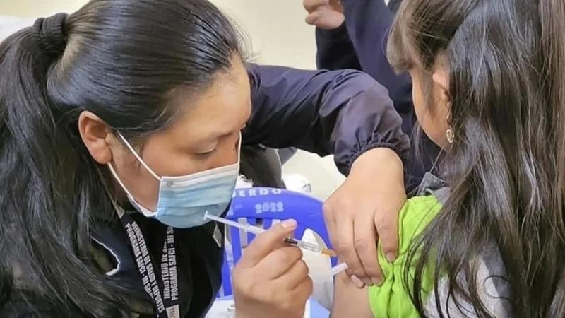 Una mujer vacunando a una niña