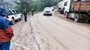 Personal policial  regulando el tráfico vehicular en una vía de lodo y tierra en la carretera