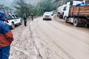 Personal policial  regulando el tráfico vehicular en una vía de lodo y tierra en la carretera