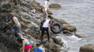 Migrantes usando flotadores caseros para cruzar por la zona rocosa de la costa