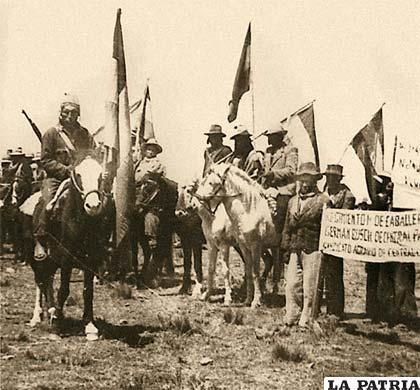 Cammpesinos a caballo y a pie portando banderas