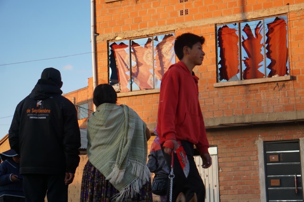 Vecinos caminan frente a una vivienda con los ventanales destruidos por la onda expansiva