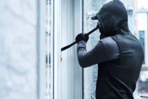 Un ladrón intentando entrar a una casa