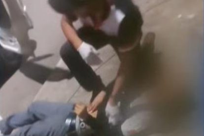 Un señor revisando a otra persona tendida en el suelo