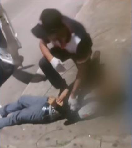 Un señor revisando a otra persona tendida en el suelo