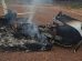 Restos quemados y humeantes de una avioneta monomotor destruida en un terreno de tierra rojiza
