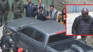 Un grupo de periodistas filamando un vehículo negro .