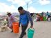 personas con baldes y tachos de agua